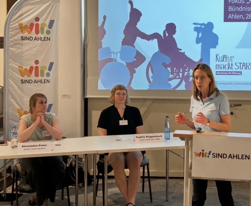 Foto: Drei Personen vor einer Präsentation mit einem Beamer