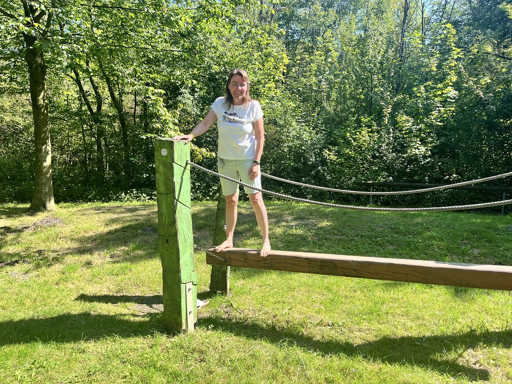Foto: Brigga Kazmiercak auf einem an Seilen angehängten Holzbalken
