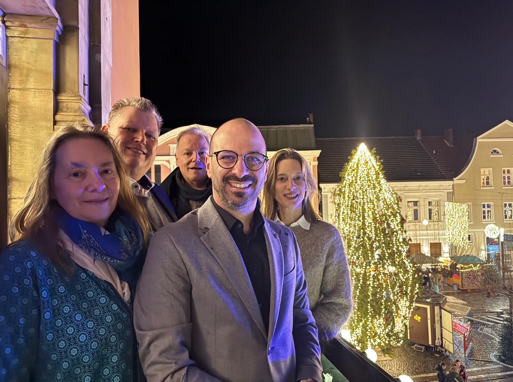 Foto: Gruppenbild mit beleuchtetem Weihnachtsbaum und Blick auf den Marktplatz