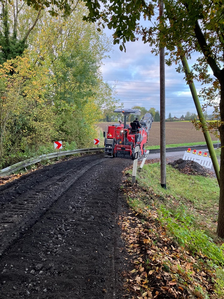 Foto. Wirtschaftsweg an einem Feld mit einer Baumaschine