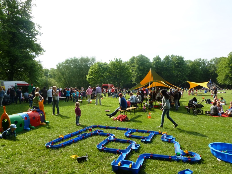 Foto: Wiese mit Kindern und Spielgeräten aus dem Spielmobil