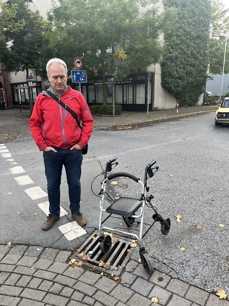 Foto: Frank Buntrock mit einem Rollator, der in einem Gulli feststeckt