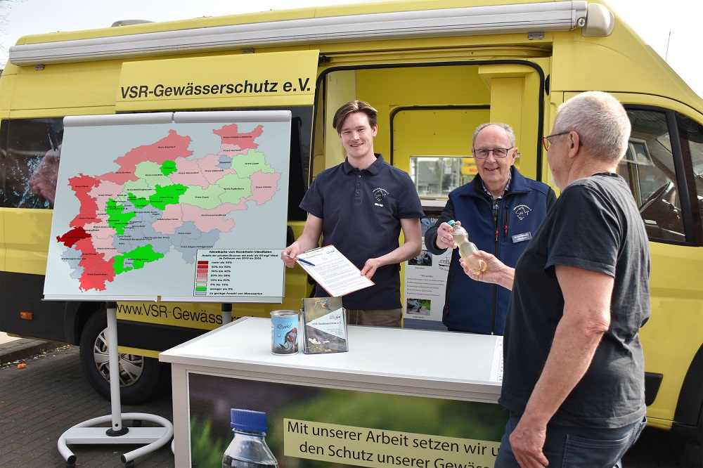 Foto: Drei Männer vor einem gelben Auto mit einer Karte