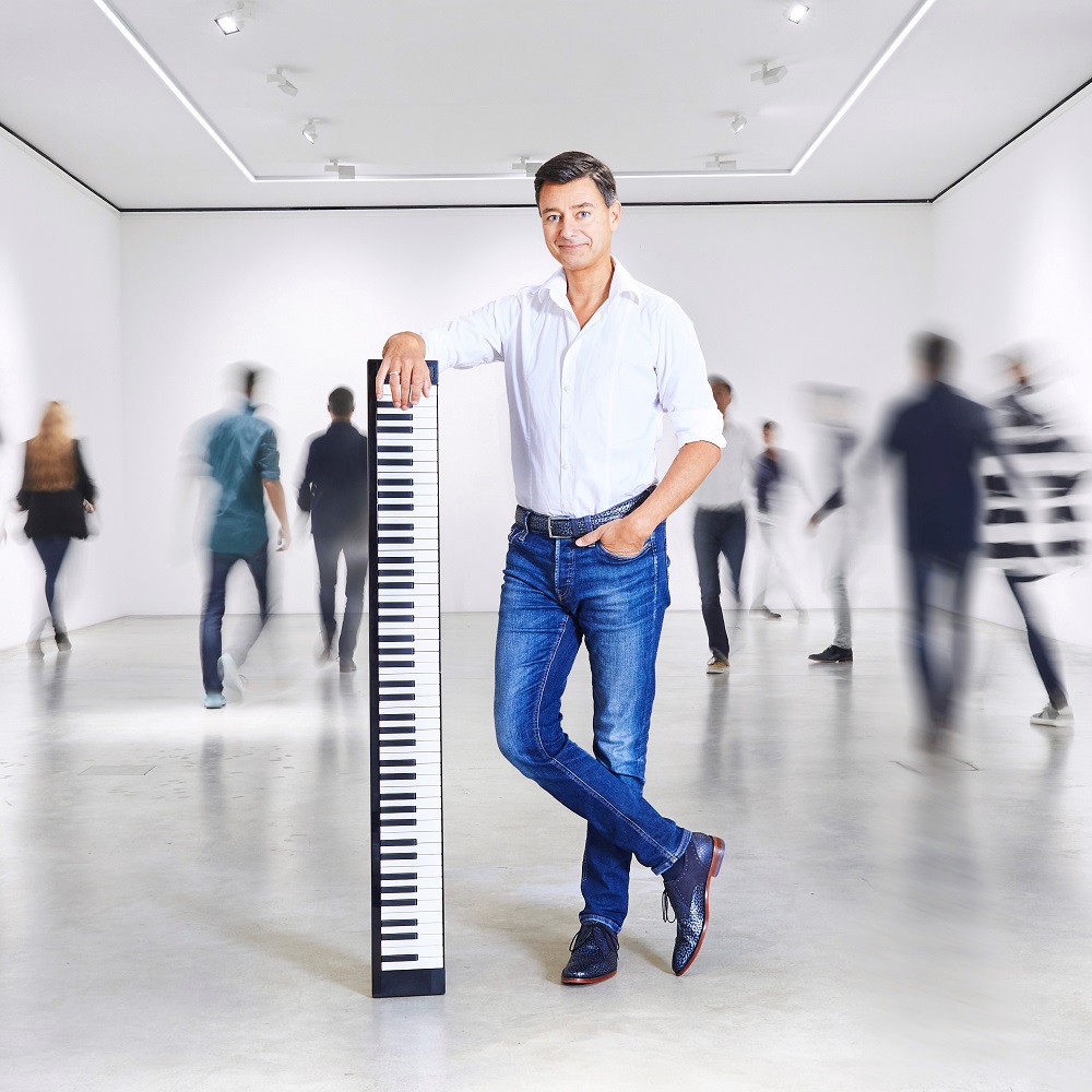 Foto: Mann in Jeans auf eine Tastatur gelehnt