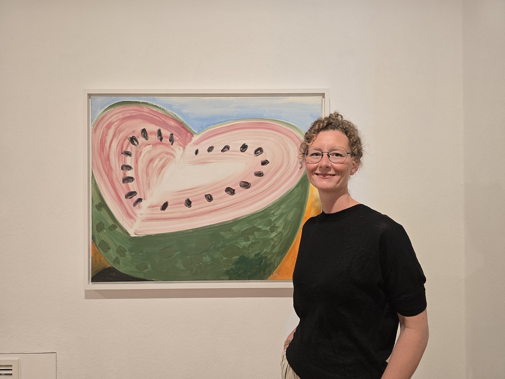 Foto: Maike Kokoska vor einem Gemälde mit einer aufgeschnnittenen Wassermelone