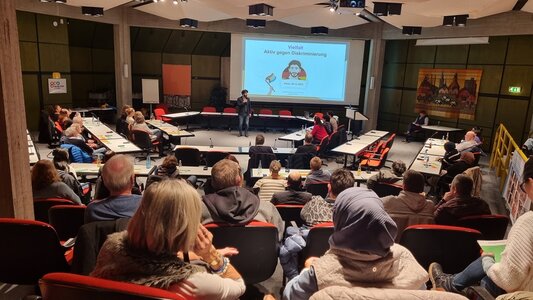 Foto: Ratssaal von hinten über die Besucher hinweg, mit Blick auf eine Leinwand