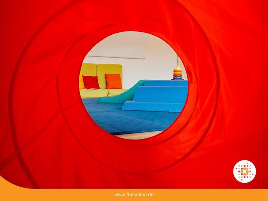 Foto: roter Hintergrund mit Liegewiese und Kinderspielzeug