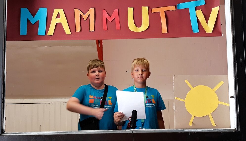 Foto: 2 Jungen unter dem Schild "Mammut-TV"
