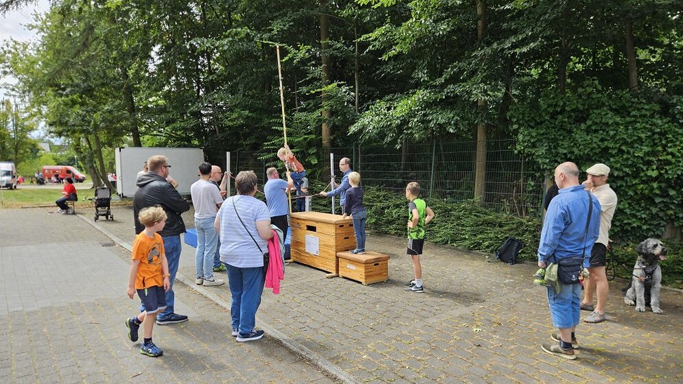 Foto: Menschengruppe und Holzböcke aus einer Turnhalle