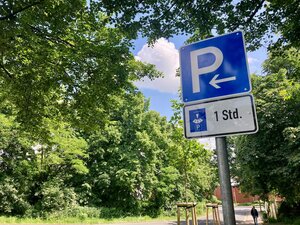 Foto: Parkschild mit einer Parkscheibe vor Bäumen
