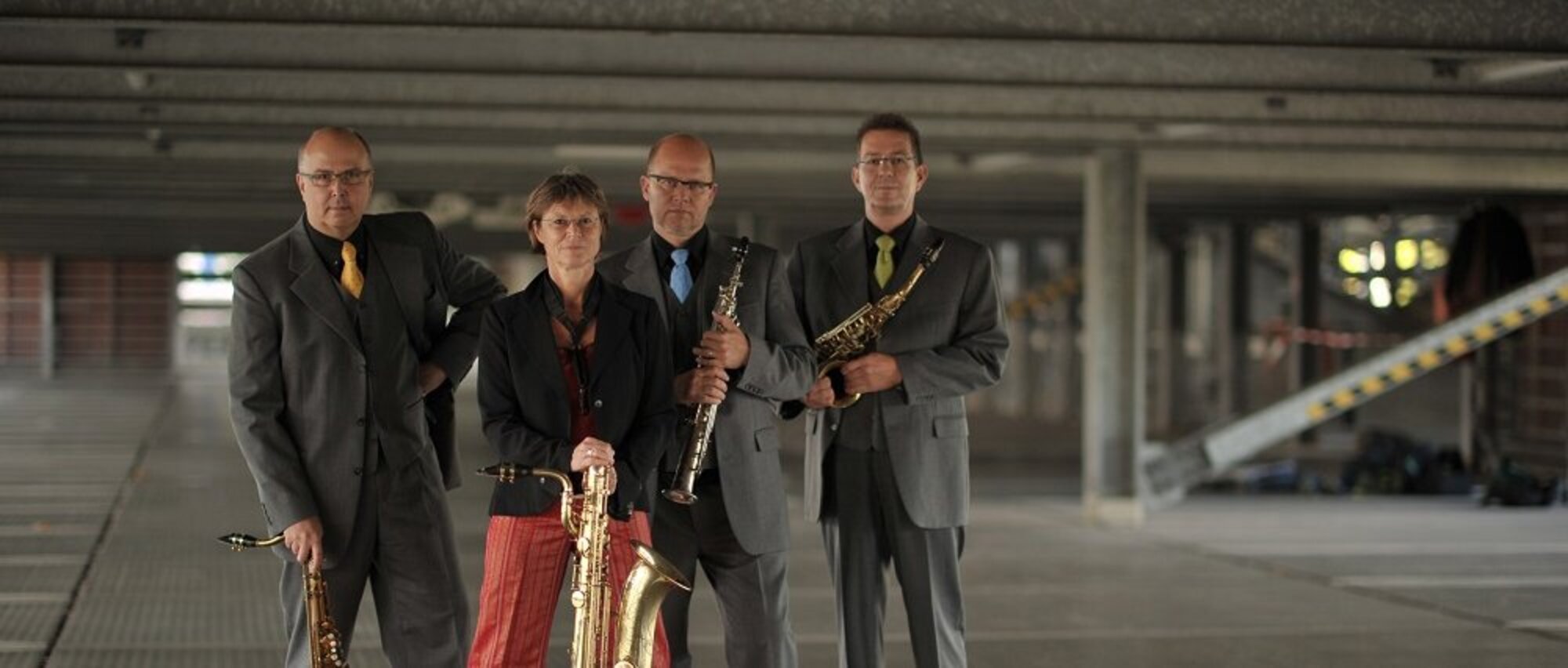 Foto: 4 Personen mit Blasinstrumenten in einer Halle