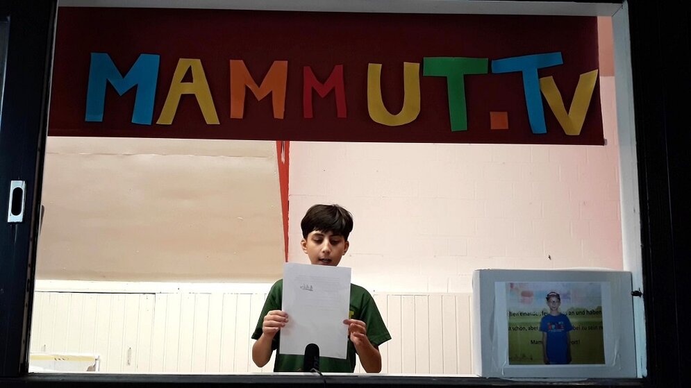 Foto: ein Junge liest von einem Zettel ab