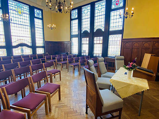 Foto: Tisch mit Stühlen und dahinter Stuhlreihen im alten Ratssaal