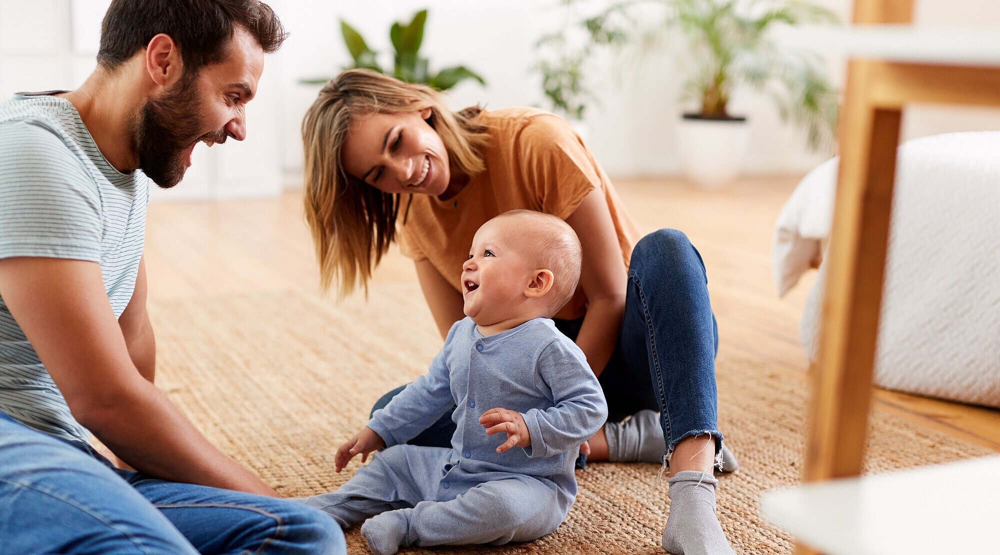 Foto: Eltern sitzen mit einem Baby auf dem Fußboden