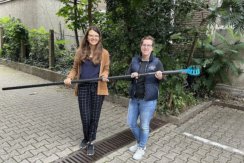 Foto: Lea Feldhaus und Anna Shalimava (l.) machen es vor: Mit dem Obstpflücker lassen sich Äpfel und Birnen am besten vom Baum holen.