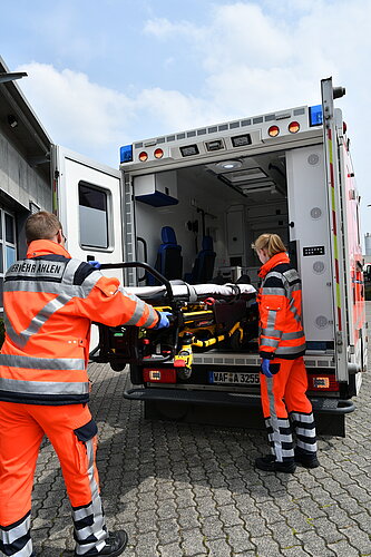 Foto: 2 Notfallsanitäter am Fahrzeug mit einer Trage