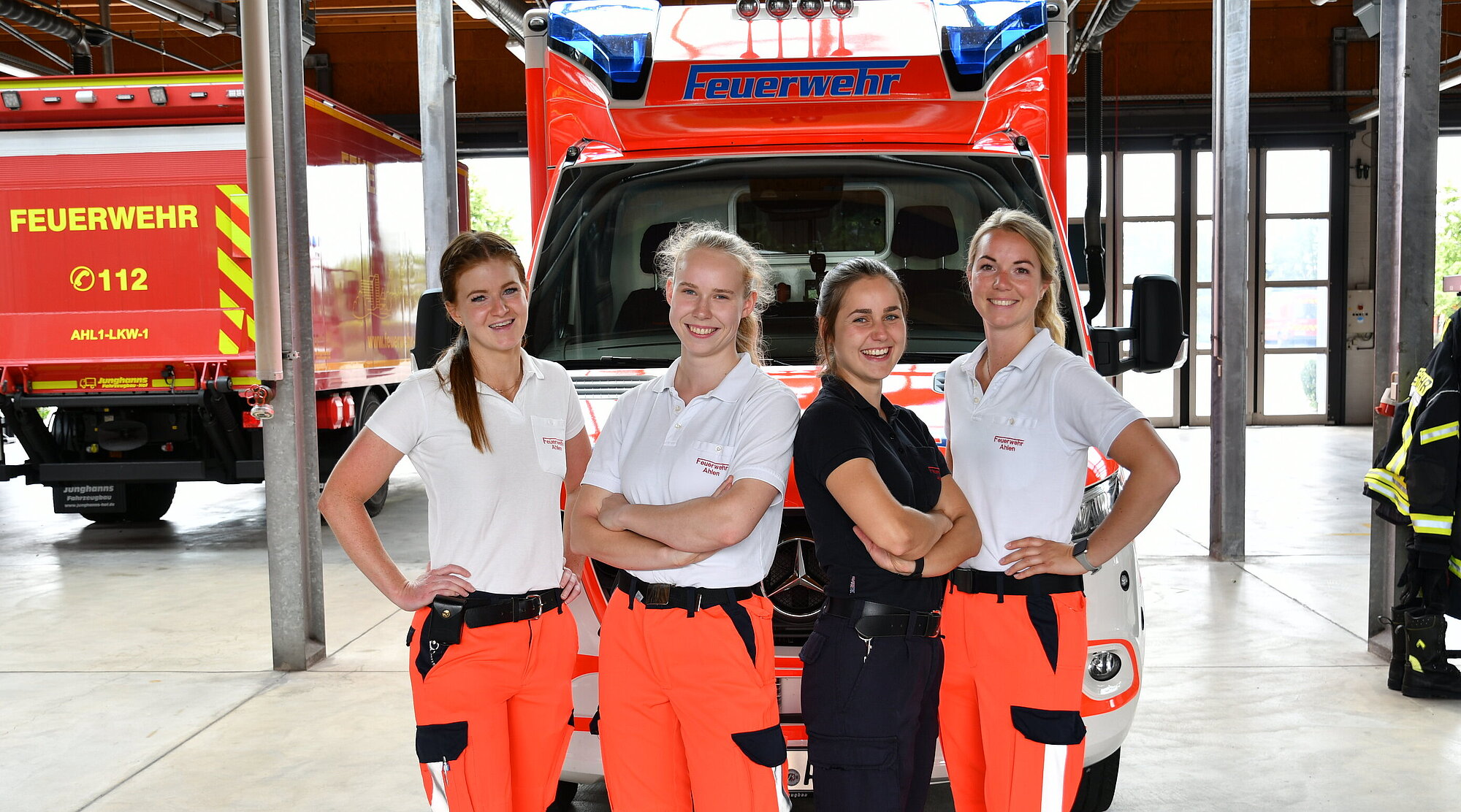 Foto: 4 Notfallsanitäterinnen in der Fahrzeughalle vor einem Rettungswagen