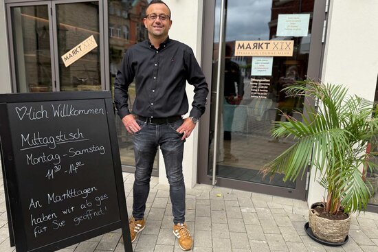 Ein Herr steht vor Restaurant mit Schild