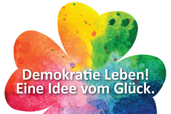 Logo: Demokratie leben - eine Idee vom Glück in einem farbigen Kleeblatt
