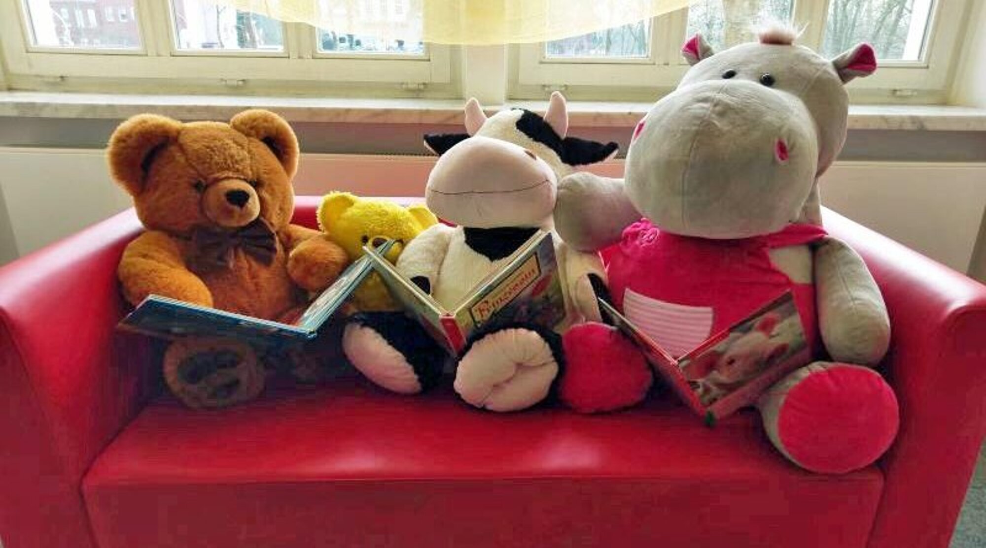Foto: Stoffbären mit Büchern auf einem Sofa