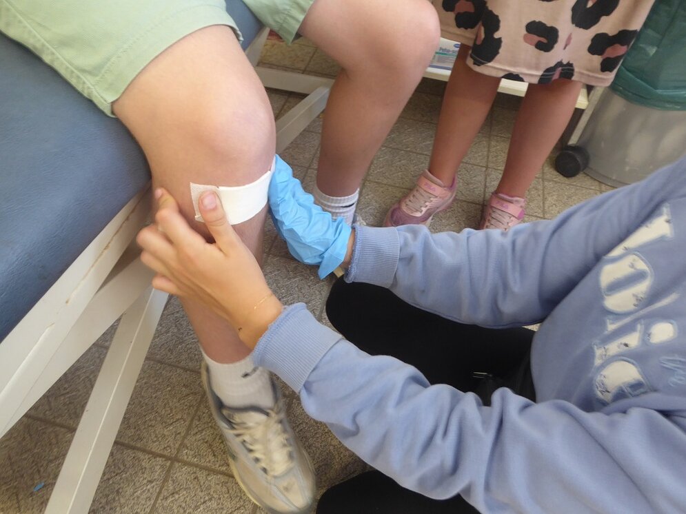 Foto: Es wird ein Pflaster auf ein Knie geklebt
