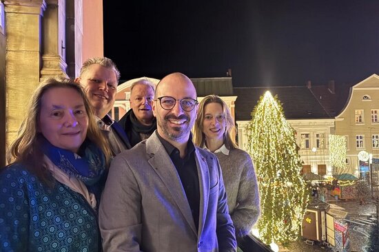 Foto: Gruppenbild mit beleuchtetem Weihnachtsbaum und Blick auf den Marktplatz
